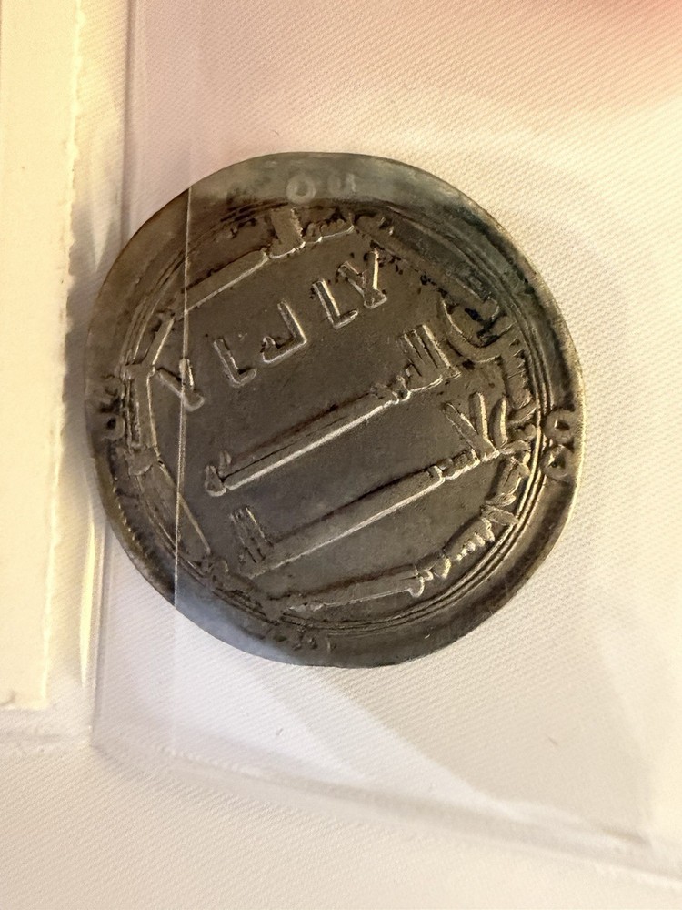 An Abbasid silver dirham featuring Arabic script and central dagger motifs.
